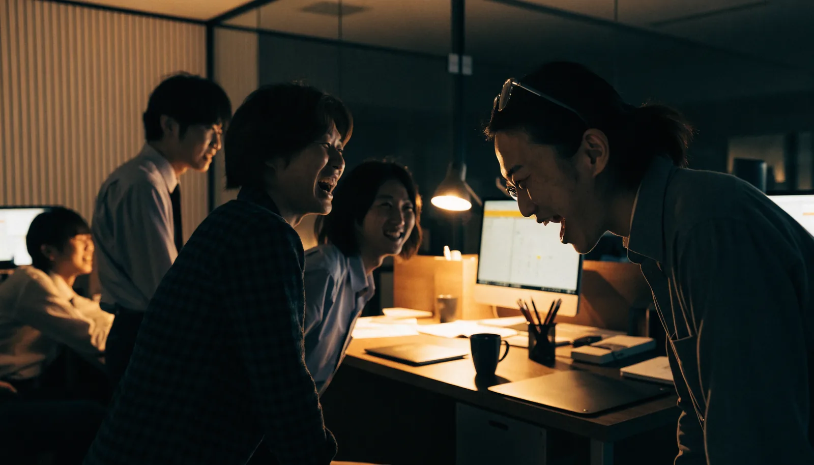 夜のオフィスで語り合うチーム